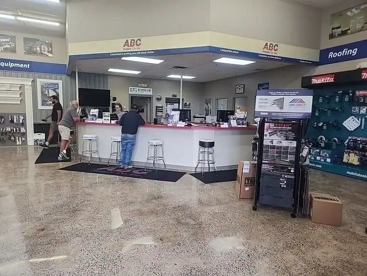 A hardware store counter with three people standing, shelves displaying tools and equipment, and signs for roofing and equipment. The speckled floor features epoxy flooring&mdash;popular in Hartford, New Haven, CT&mdash;while the counter has barstools and products on display.
