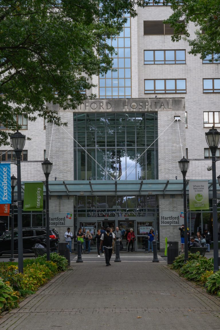 People walk toward the main entrance of the Hartford Hospital building.