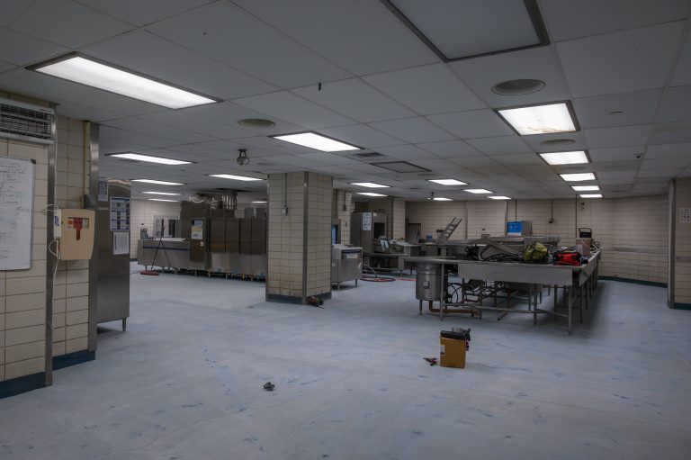 A large commercial kitchen facility features industrial dishwashing equipment and stainless tables.